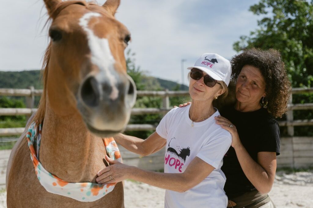 Deux femmes caressent un cheval lors d'une séance d'équithérapie HOPE