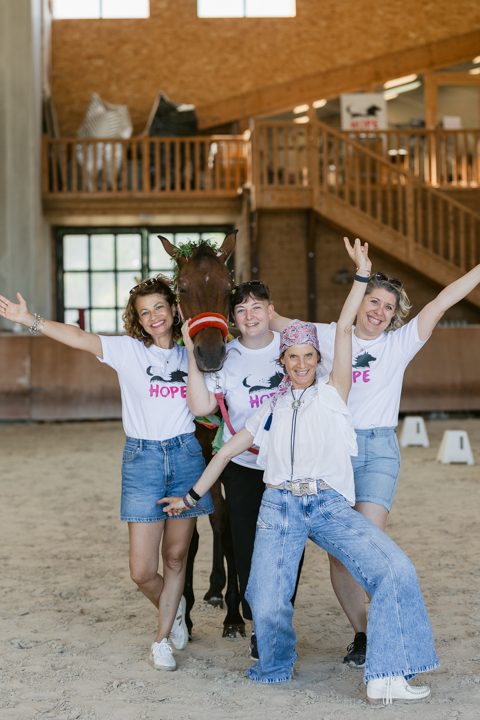 Quatre femmes en tee-shirt HOPE, bras levés et souriantes, dans un manège couvert